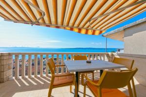 a table and chairs on a balcony with a view of the ocean at Guest house Lenka in Brela