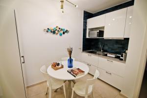 - une cuisine blanche avec une table et des chaises blanches dans l'établissement Bovio 33 Napoli art apartment, à Naples