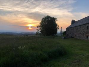an old building in a field with the sunset in the background at maison de campagne Mezenc. in Saint-Front
