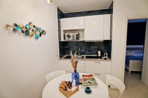 - une cuisine blanche avec une table et un vase dans l'établissement Bovio 33 Napoli art apartment, à Naples