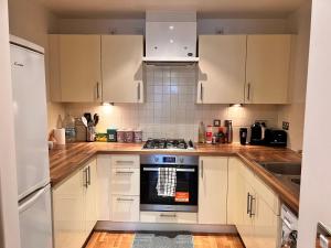 a kitchen with white cabinets and a stove top oven at Entire Apartment next to Canary Wharf in London in London