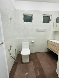 a white bathroom with a toilet and a sink at Matheera Holiday Home in Jaffna