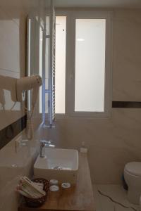 a white bathroom with a sink and a window at Hotel 999 in Prato