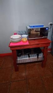 - une table rouge avec des assiettes et un four micro-ondes dans l'établissement Villalobos Hotel Managua, à Managua