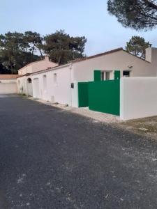 ein Gebäude mit einer grünen und weißen Wand neben einer Straße in der Unterkunft Calme et tranquillité -Ile de Ré in Rivedoux-Plage