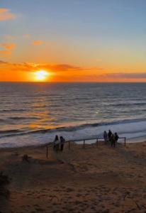 a group of people standing on the beach at sunset at APARTAMENTO DE AMY CON VISTA AL MAR 2 in Huelva
