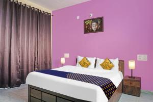 um quarto com uma cama grande e paredes roxas em OYO MYRA SERVICED APARTMENTS em Lohogaon