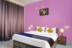 - une chambre avec un grand lit aux murs violets dans l'établissement OYO MYRA SERVICED APARTMENTS, à Lohogaon