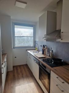 uma cozinha com armários brancos, um lavatório e uma janela em ruhige Privatzimmer im Apartment Natur Messe Zentral em Düsseldorf