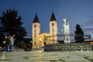 a church with a statue in front of it at Pansion Vesna&Vlado Ostojic in Međugorje