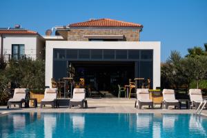 una piscina con sedie e tavoli di fronte a una casa di Kotinos Beach Hotel a Gokceada Town