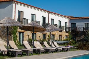 una fila di sedie a sdraio e ombrelloni accanto alla piscina di Kotinos Beach Hotel a Gokceada Town