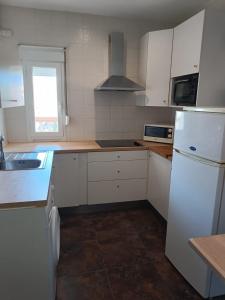 a kitchen with white cabinets and a white refrigerator at La Casa de Maia in Freila