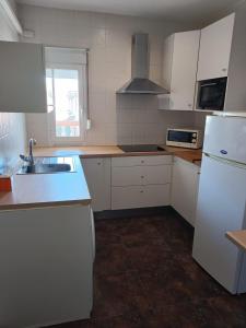 a white kitchen with a sink and a refrigerator at La Casa de Maia in Freila