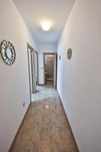 a hallway with white walls and a clock on the wall at Apartamentos Camelle in Camelle
