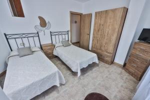 a bedroom with two beds and a television in it at Apartamentos Camelle in Camelle