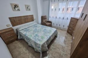 a bedroom with a bed and a chair in it at Apartamentos Camelle in Camelle