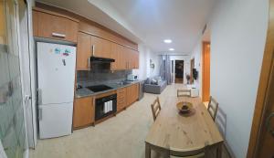 a kitchen with a wooden table and a white refrigerator at Apartamento con piscina y cerca de la playa in Canet de Berenguer