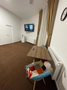 a room with a table and a chair and a tv at Resedinta Cina in Braşov