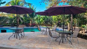 eine Gruppe von Tischen und Stühlen mit Sonnenschirmen neben einem Pool in der Unterkunft Suite Jr Aire de Montaña 6 - Hot Springs in Ahuachapán