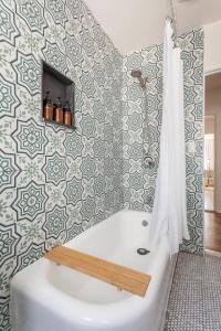 a bathroom with a tub and a tile wall at Culver City 1920s Bungalow on Shady Cul-du-Sac in Los Angeles