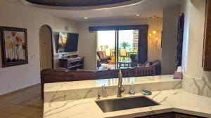 a kitchen with a sink and a living room at Bella Sirena 304-A - Elegant Oceanview Condo on Sandy Beach in Puerto Peñasco