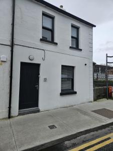 a white house with a black door and windows at Number33 in Galway