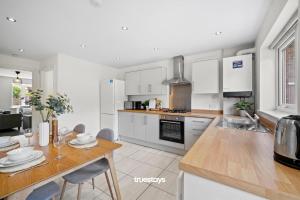 a kitchen with white cabinets and a table with chairs at Greaves House by Truestays - 3 Bedroom House in Failsworth, Manchester in Manchester