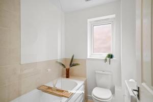 uma casa de banho com uma banheira, um WC e uma janela. em Greaves House by Truestays - 3 Bedroom House in Failsworth, Manchester em Manchester