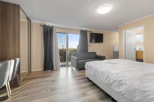sypialnia z łóżkiem, krzesłem i oknem w obiekcie S1 Motel w mieście Brisbane