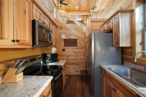 a kitchen with wooden cabinets and a stainless steel refrigerator at Charming Modern Lux Cabin Hot Tub FirePit Games in Runaway Bay
