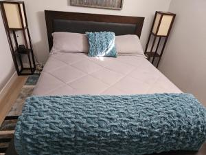 Una cama con una manta azul encima. en Newly Renovated Suite en Regina