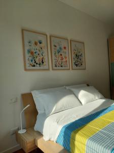 1 cama en un dormitorio con 3 cuadros en la pared en Casa Mappamondo, en Lecco