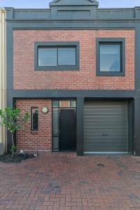 a red brick house with two garage doors at Halifax Muse Pet Friendly Townhouse in Adelaide