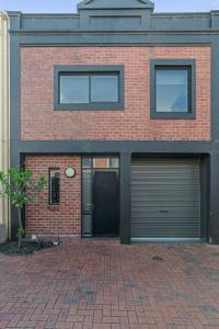 una casa de ladrillo rojo con dos puertas de garaje en Halifax Muse Pet Friendly Townhouse, en Adelaida