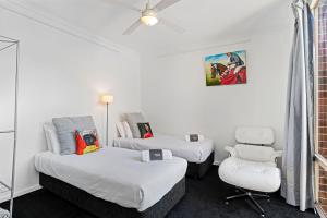 una habitación de hotel con 2 camas y una silla en Halifax Muse Pet Friendly Townhouse, en Adelaida