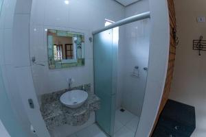 La salle de bains est pourvue d'un lavabo et d'une douche en verre. dans l'établissement Casa 3/4 aconchegante no Vale do Capão, à Palmeiras