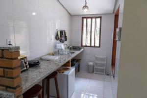 - une cuisine blanche avec un comptoir et un évier dans l'établissement Casa 3/4 aconchegante no Vale do Capão, à Palmeiras