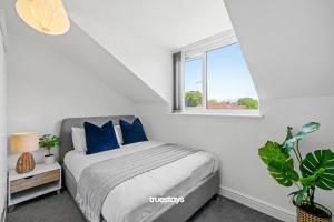 a bedroom with a bed with blue pillows and a window at 6 Sarah House by Truestays - 2 Bedroom Apartment - FREE Wifi & Parking in Manchester