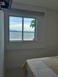 a bedroom with a window with a view of the ocean at Apartamento Arraial do Cabo in Arraial do Cabo