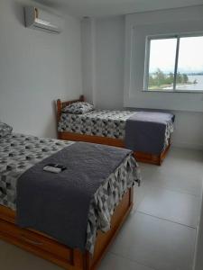 a room with three beds and a window at Apartamento Arraial do Cabo in Arraial do Cabo