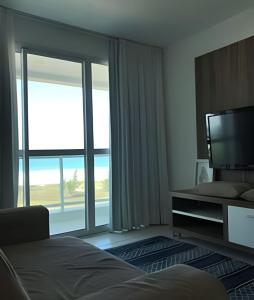 Habitación de hotel con cama y ventana grande en FLAT MANDAI CABO FRIO en Cabo Frío