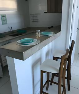 una cocina con encimera con 2 sillas y platos. en FLAT MANDAI CABO FRIO en Cabo Frío
