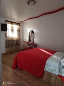 um quarto com uma cama com um cobertor vermelho em Quinta imperio del sol em Latacunga
