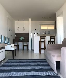 a living room with a couch and a kitchen at Flat Mandai Cabo Frio in Cabo Frio
