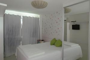 1 dormitorio con cama blanca y almohadas verdes en PRAIA DO FORTE ALTO LUXO en Cabo Frío