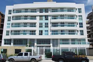 a white building with cars parked in front of it at Flat Mandai Cabo Frio in Cabo Frio