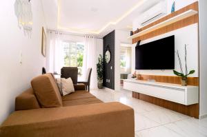 uma sala de estar com um sofá e uma televisão de ecrã plano em Apt luxo na área nobre Ingleses em Florianópolis