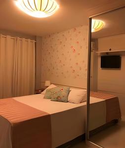 a bedroom with a bed and a mirror at PRAIA DO FORTE ALTO LUXO in Cabo Frio