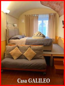 een slaapkamer met 2 bedden en een bank voor een raam bij Antiche Dimore Pisane in Pisa